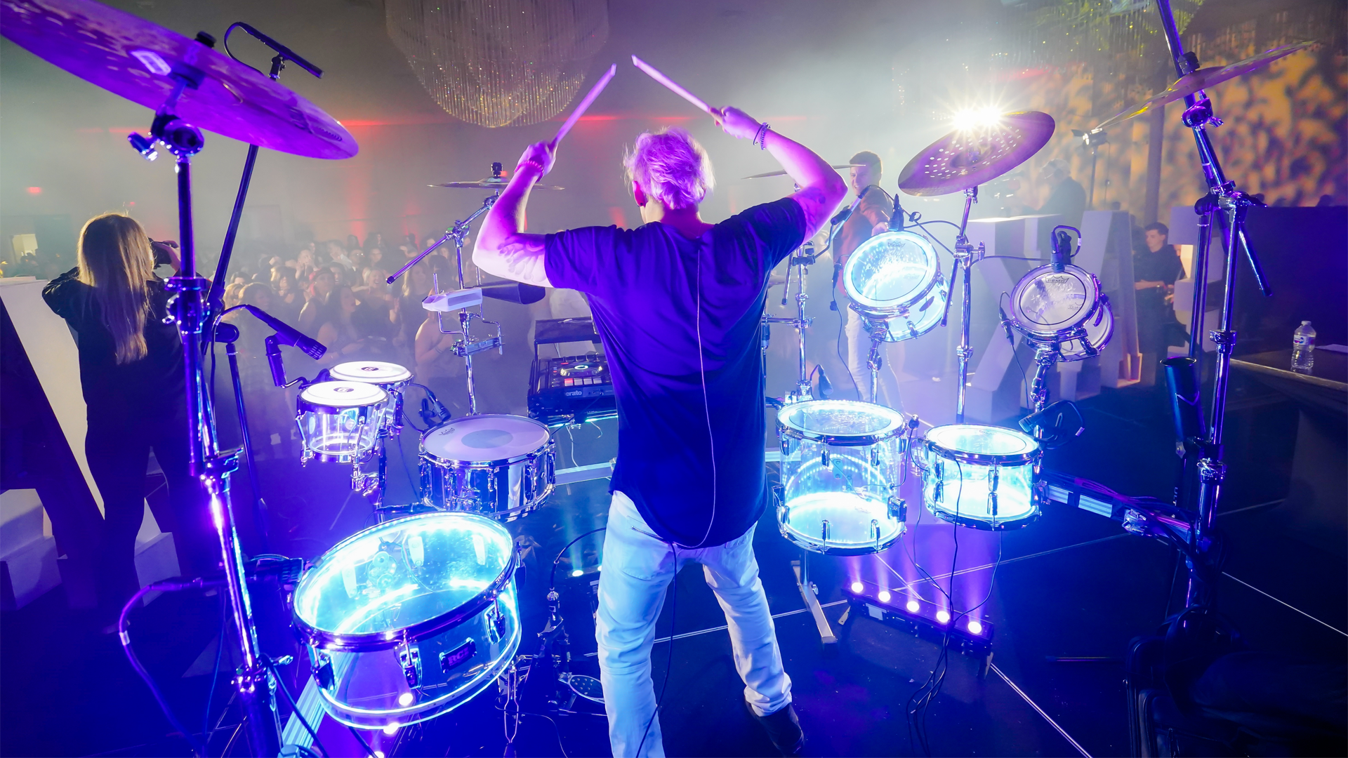 The drummer for a band, lit up with electric blue lights